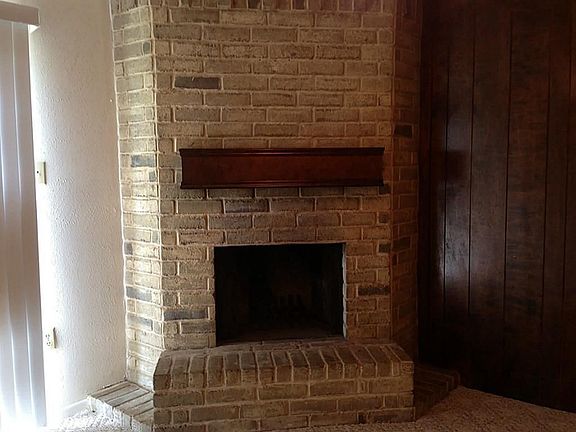 Cloose-up view of corner, woodburning fireplace with mantle.