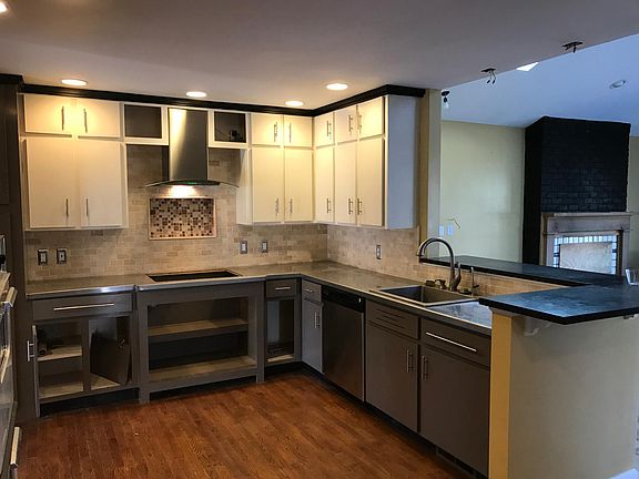 Stainless steel countertops, pre-restoration picture. New gas grill, new dishwasher, new lights, more. Kitchen opens to large den with fireplace. See later pictures below.