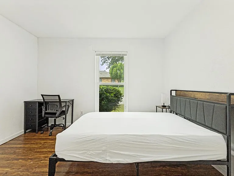 Private bedroom with wood-look flooring, a large window, and space for a desk or additional storage.