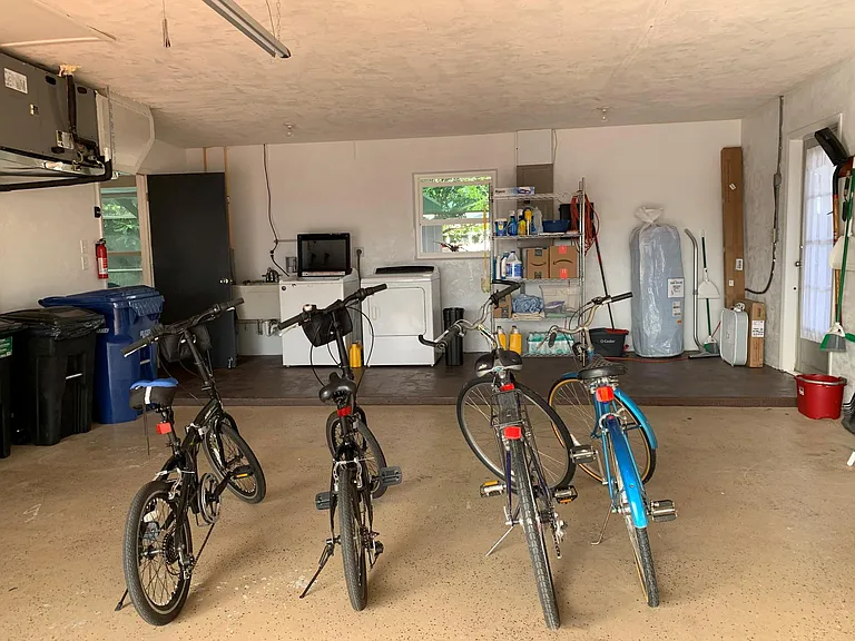 2 car garage with 4 bikes, big trash cans, recycling bin, and the laundry area with washer, drier and supplies.