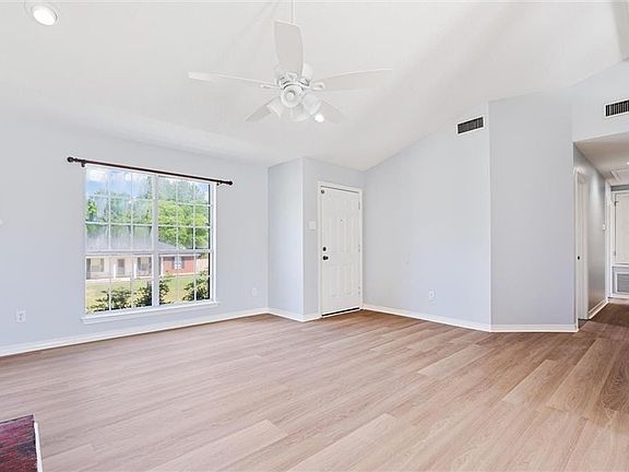 Unfurnished living room featuring ceiling fan, lofted ceiling with beams, and light hardwood / wood-style flooring