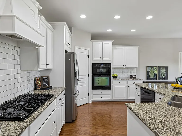 This expansive kitchen features beautiful backsplash, granite countertops & an oversized island!