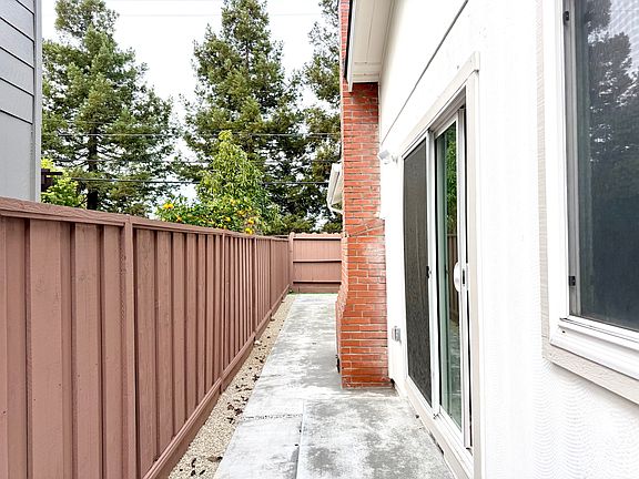 Side walkway with brand new fence, concrete and stones