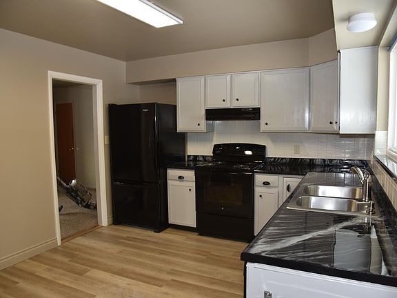 Newly refurbished kitchen with new electric range and stainless steel sink with disposal.