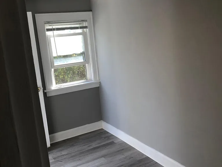 small office/den at back of apartment with ceiling fan and window