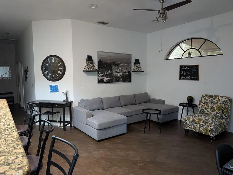 Spacious shared living area with a sectional sofa, accent seating, and an arched window for natural light.