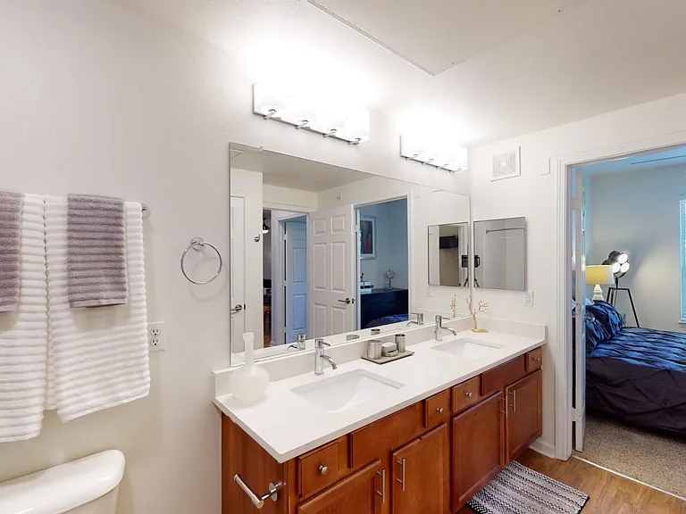 Apartment bathroom with wood-style flooring and double sinks.
