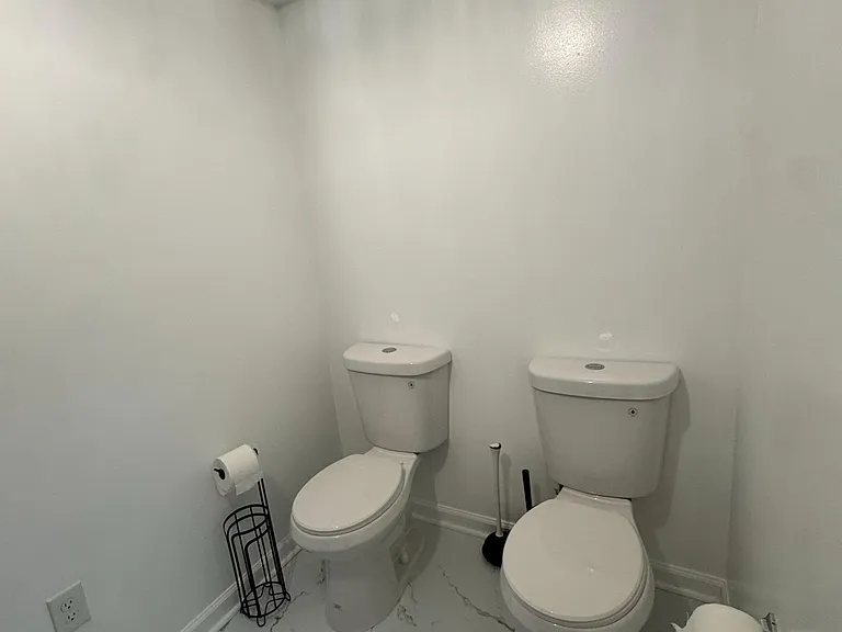 Convenient shared bathroom with dual toilets and durable tile-look flooring for easy upkeep in a high-traffic home.