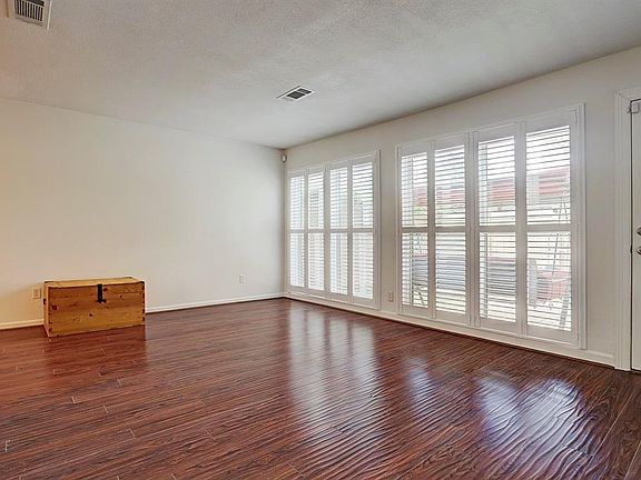 Natural light bathes the living room featuring wall of windows overlooking the back patio, custom shutters and laminate wood floor