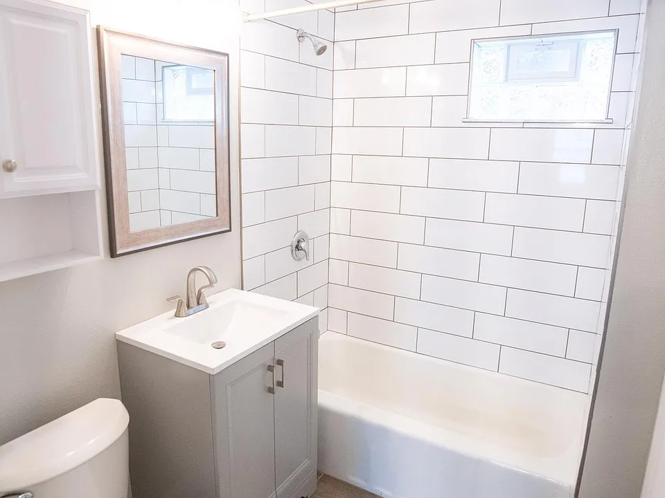 Bright white bathroom with subway tiled bath, new vanity and toilet