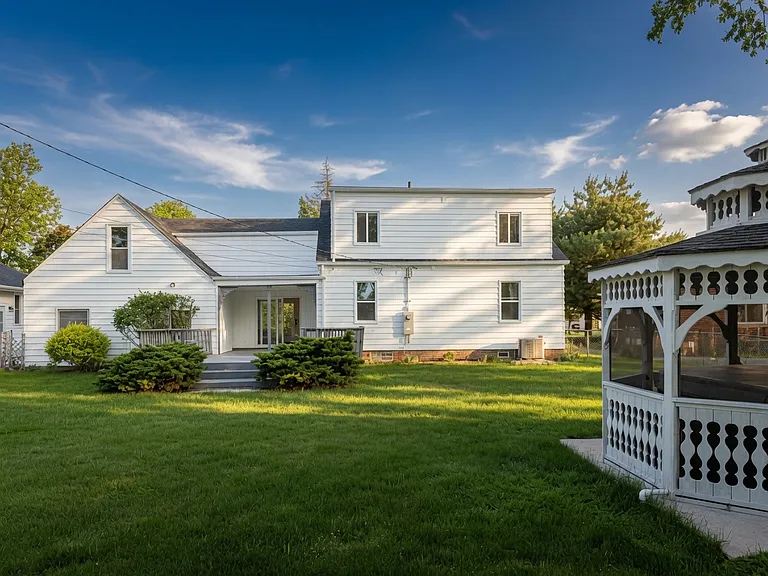 Large sunny backyard featuring a screened gazebo, mature landscaping, and plenty of room to play or relax.