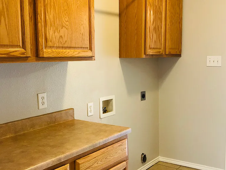 Large Laundry room and mudroom situated off the garage entrance. Dedicated space for laundry folding and extra cabinet storage.