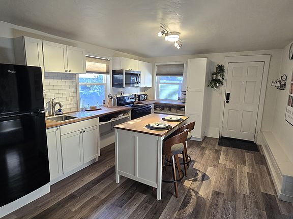Updated kitchen with full-size appliances, butcher-block counters, subway tile, and an island with seating _ bright, clean, and fully stocked for everyday living.