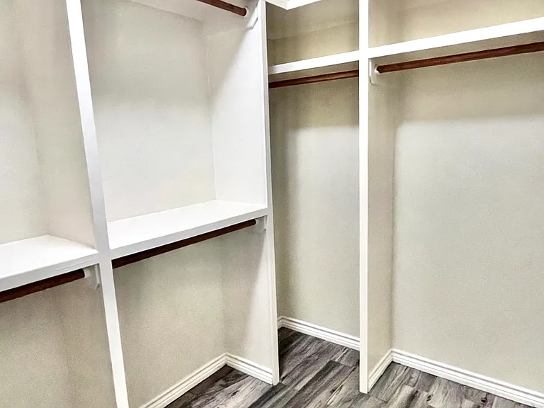 Generous walk-in closet with multiple hanging rods, build-in shelving, and plenty of storage space
