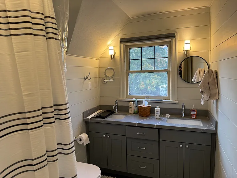 Upstairs bathroom with claw-foot bathtub and shower and double vanities.