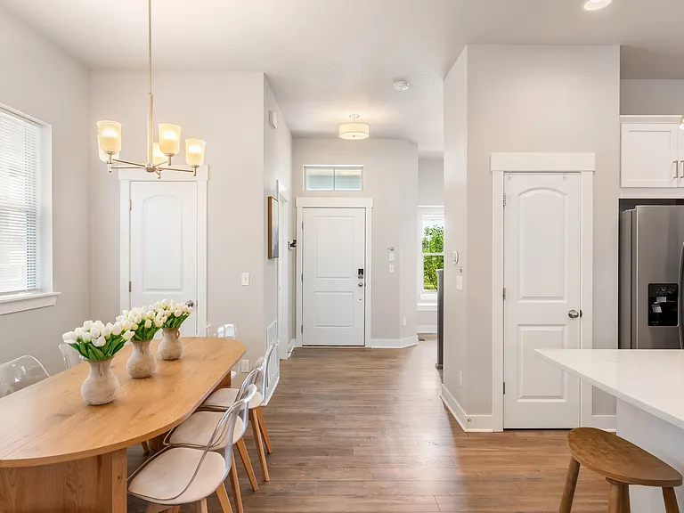 Enjoy a bright, modern kitchen with a spacious island and stainless steel appliances. The adjacent dining area features a large wooden table and comfortable chairs, perfect for sharing special moments bathed in natural light.