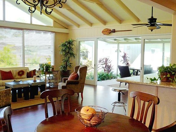 View from dining area across Great Room and its exposed bean ceiling, kitchen work island and cottag