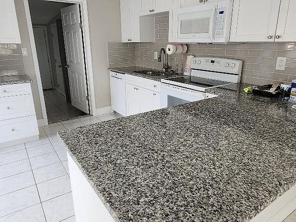 Kitchen counter, stove, dishwasher, garbage disposal. The doorway leads into the 3rd bedroom, 2nd bath and laundry area.