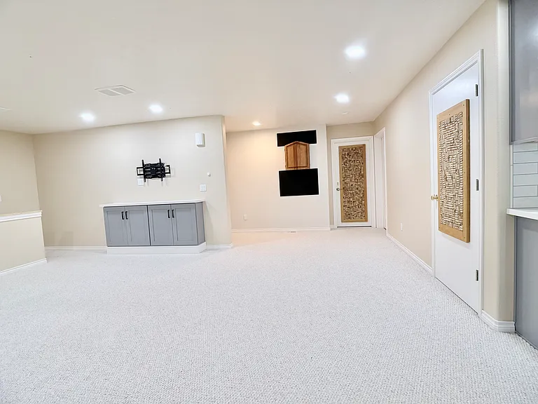 Expansive lower-level living space featuring a generous lounge area, pool table, dartboard, and a well-appointed bar with wine fridge for effortless entertaining.