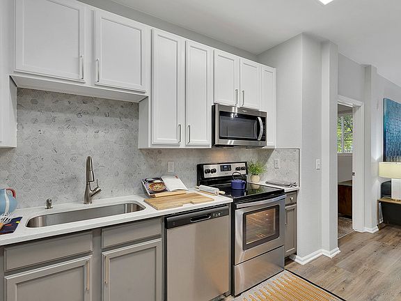 Modern kitchen with sleek appliances, elegant cabinetry, and stylish hexagonal backsplash, showcasing open-concept design.