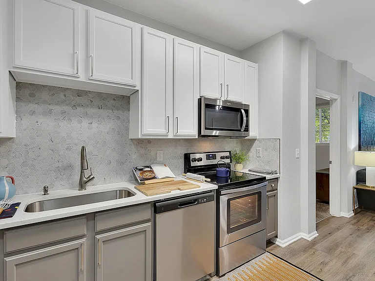 Modern kitchen with sleek appliances, elegant cabinetry, and stylish hexagonal backsplash, showcasing open-concept design.