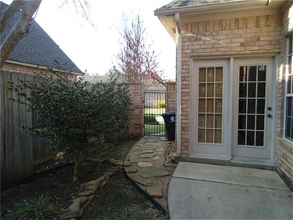 French doors into kitchen area, walkway leads to wrought iron fence with access to front yard