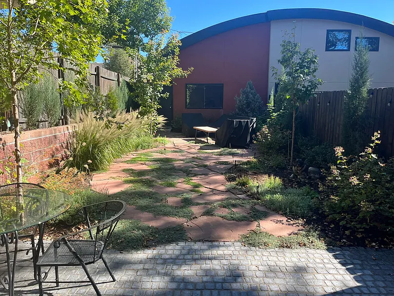 Back patio with flagstone garden and tree for shade. Detached garage.