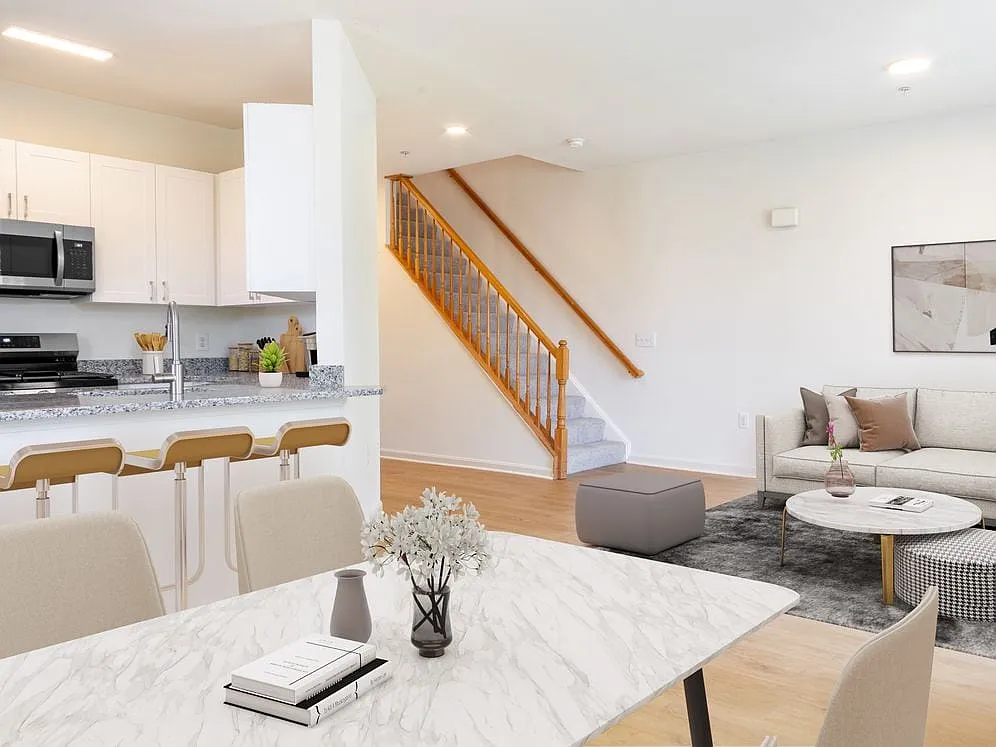 Renovated Package I kitchen, living, and dining areas with white cabinetry, grey granite countertops, stainless steel appliances, and hard surface plank flooring - Avalon Russett