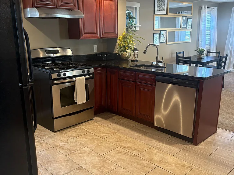 Open kitchen with ample cabinetry, stainless appliances, and a peninsula sink that connects to the dining area.
