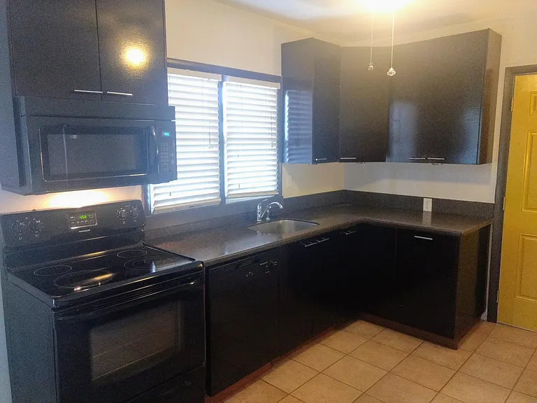 Kitchen area, floor is tile, cabinets are stained wood.
