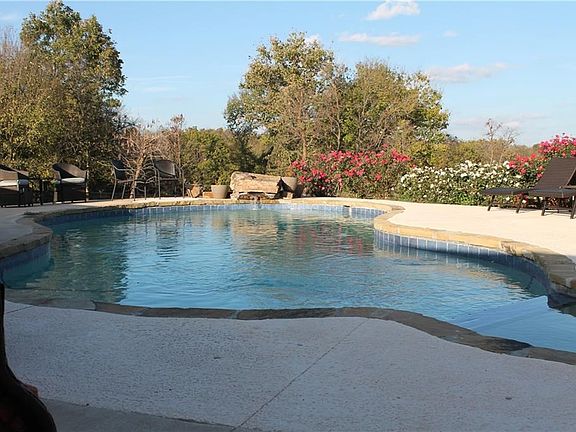 Heated gunite pool features a built in hot tub, natural stone coping, diving rock and waterfall.