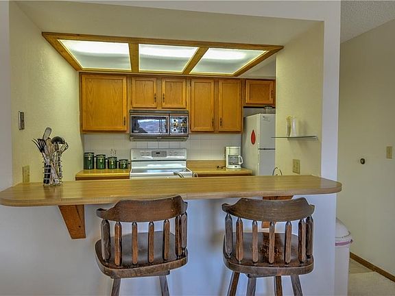 The kitchen holds a full complement of appliances, and a breakfast bar.