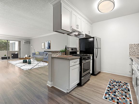 Custom tiled kitchen with view of hardwood floored living room and balcony.