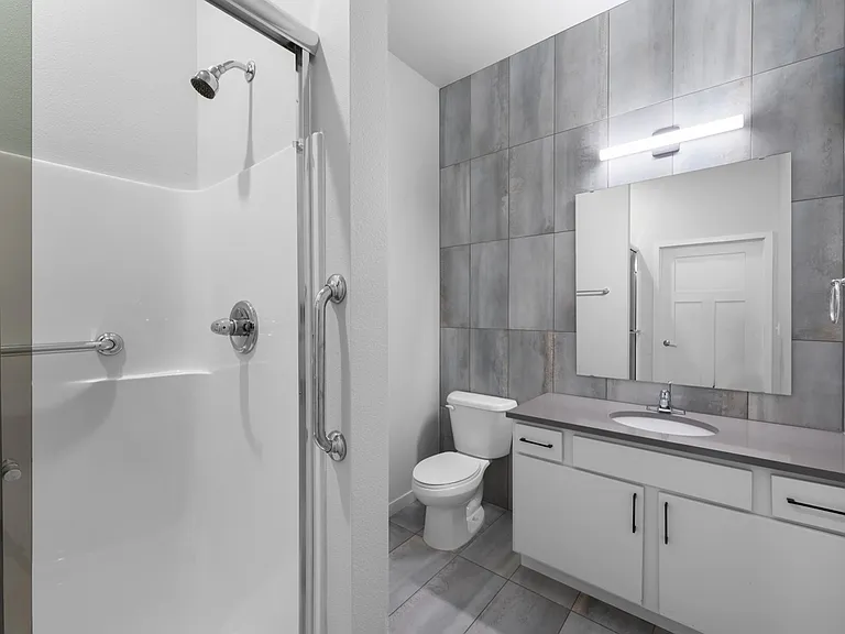 Modern and sleek bathroom featuring elegant gray tiles, a stylish vanity with ample storage, and a spacious walk-in shower. Modern and sleek bathroom featuring elegant gray tiles, a stylish vanity with ample storage, and a spacious walk-in shower.