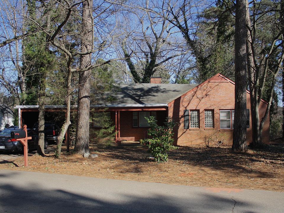 House from the street. The covered carport is on the left and a large unfenced front yard is to the right.