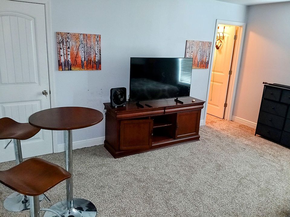 Carpeted common area with TV console, accent art, and a small bistro tableideal for relaxing or casual meals.