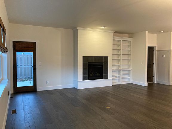 Living room with gas fireplace, built-in shelving and door to back patio
