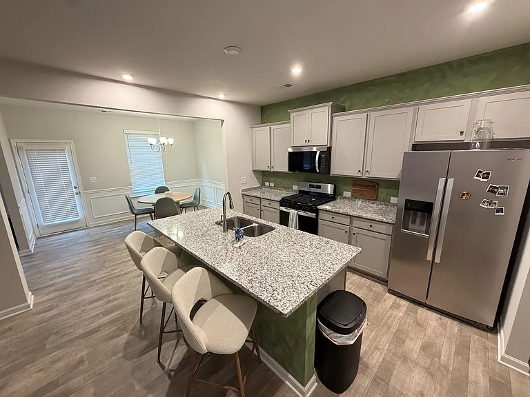 Open-concept kitchen with granite-look island seating, stainless appliances, ample cabinetry, and an adjacent dining nook.