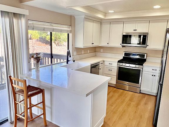 Kitchen view from dining room. Appliances include: refrigerator, dishwasher, range and microwave. Kitchen includes bar-height counter seating.