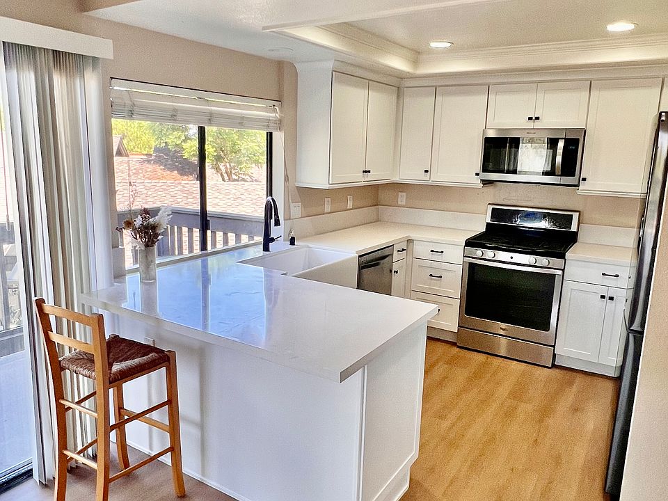Kitchen view from dining room. Appliances include: refrigerator, dishwasher, range and microwave. Kitchen includes bar-height counter seating.