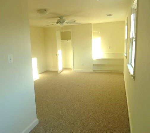 View of bedroom seen from extension area looking east toward closet, windows on right