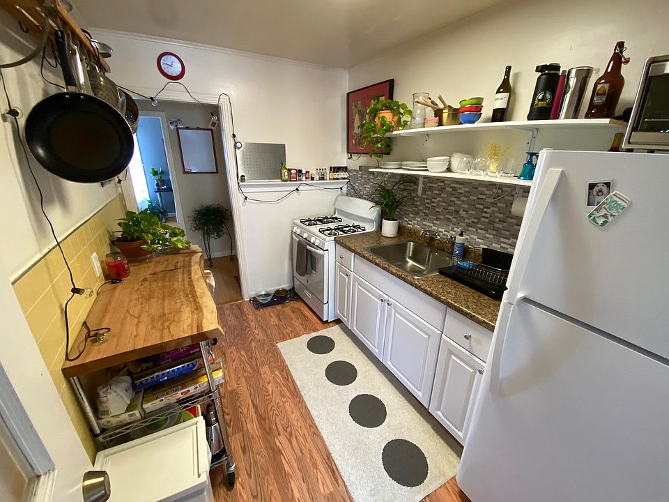 Galley kitchen with large fridge, gas stove and hardwood floors (former tenant furniture/set up)