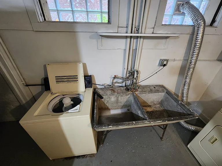 Basement lower unit laundry room washer and sink.
