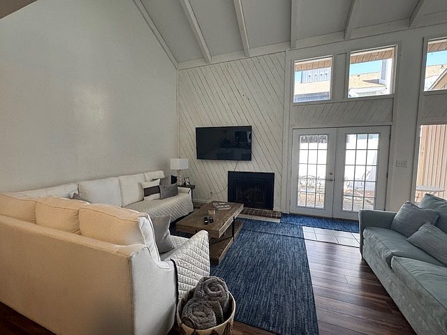 Modern living room, vaulted ceiling hardwood floors, fireplace, tv. Doors to patio.