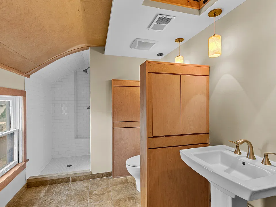 Updated bathroom with walk-in tiled shower, modern fixtures, and warm wood accents.