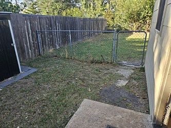 Walking out of the mudroom. There is a smaller fenced in area with a small storage shed. The gate leads to the backyard.