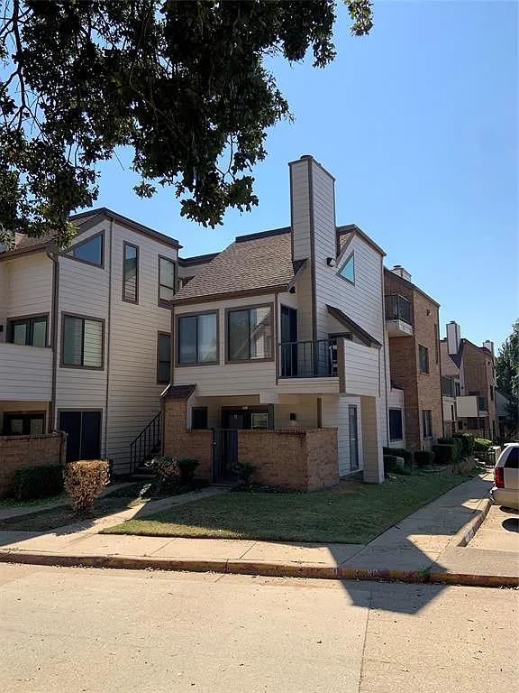 Photo 2 of 21 - 2300 Balsam Dr #G112 - Arlington, TX View of front facade featuring a shingled roof, a chimney, a balcony, brick siding, and a front yard - 2300 Balsam Dr #G112