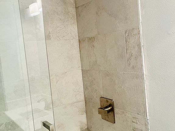 En Suite master bathroom shower with floor-to-ceiling luxury porcelain tile and brushed nickel trim.