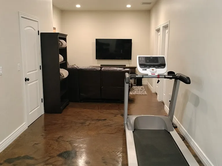 This spacious office boasts 10-foot basement ceilings, large windows for natural light, and two desks equipped with monitors and outlets for teleworking. Enjoy a treadmill for break-time exercise and a cozy fireplace to keep you comfortable.