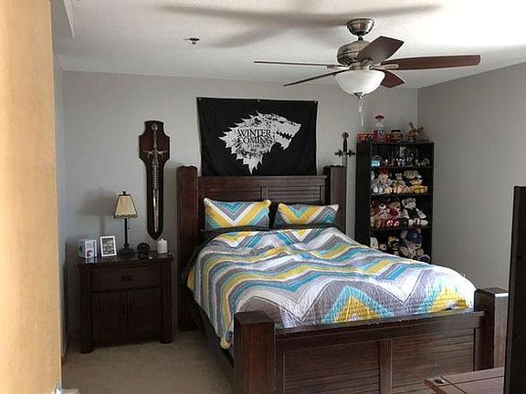 Spacious bedroom with ceiling fan and carpet floor.